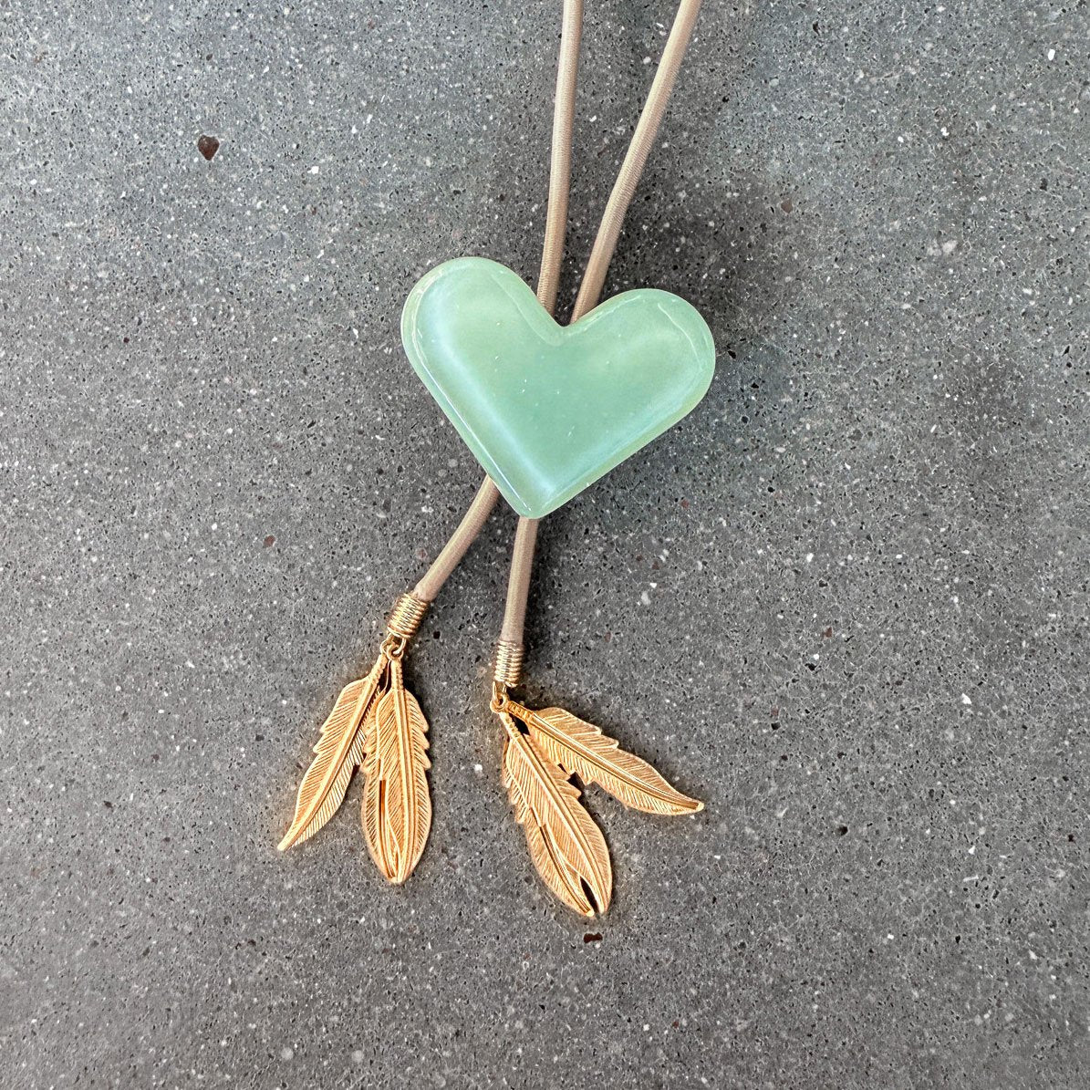 65b2bb63f348b87cbe1f70aa_clover-maven-17-glass-bolo-tie-green-heart-tan-cord-gold-tips_1784383446924.jpg