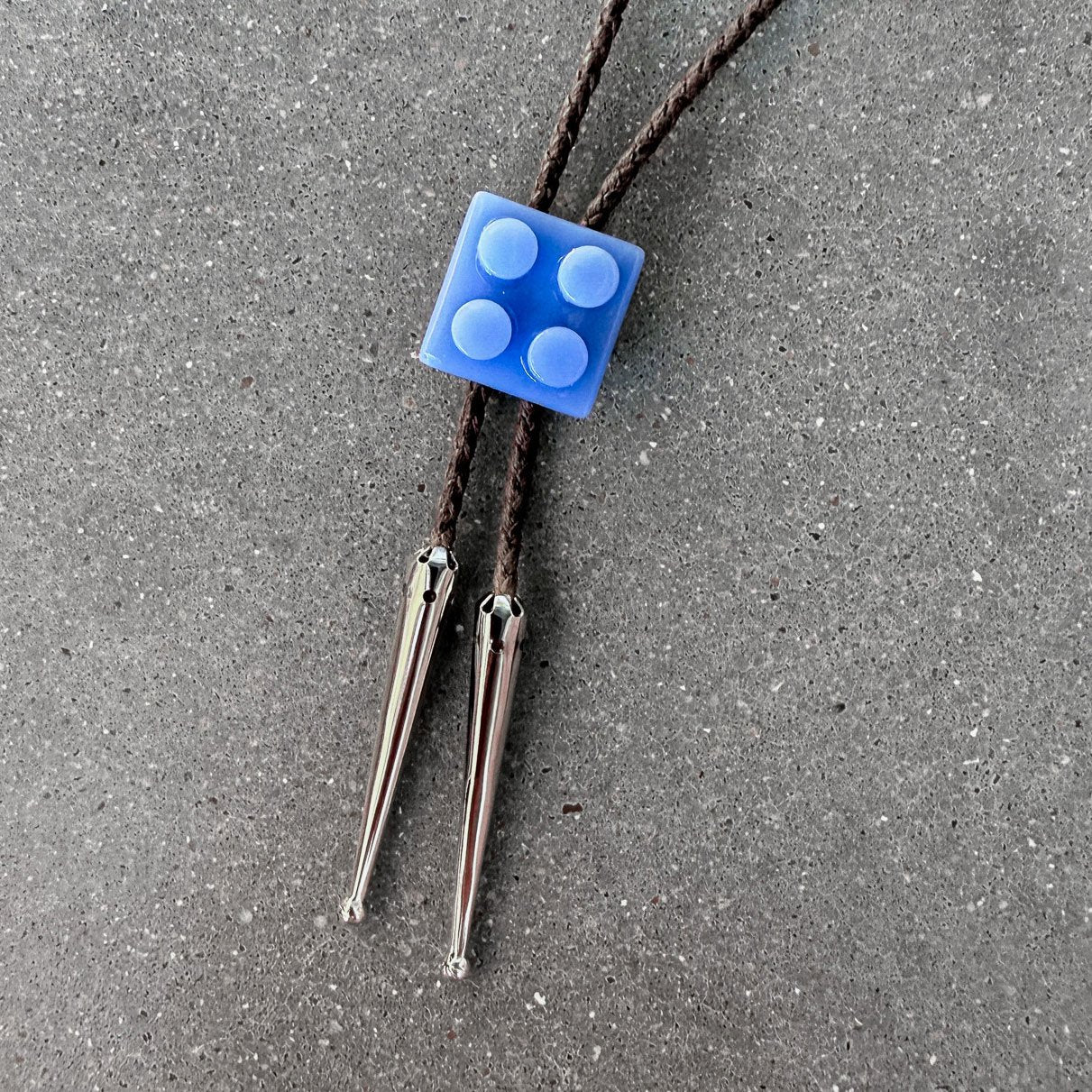 65b2bb63f348b87cbe1f70aa_clover-maven-20-glass-bolo-tie-blue-lego-brown-cord-silver-tips_1784394017681.jpg