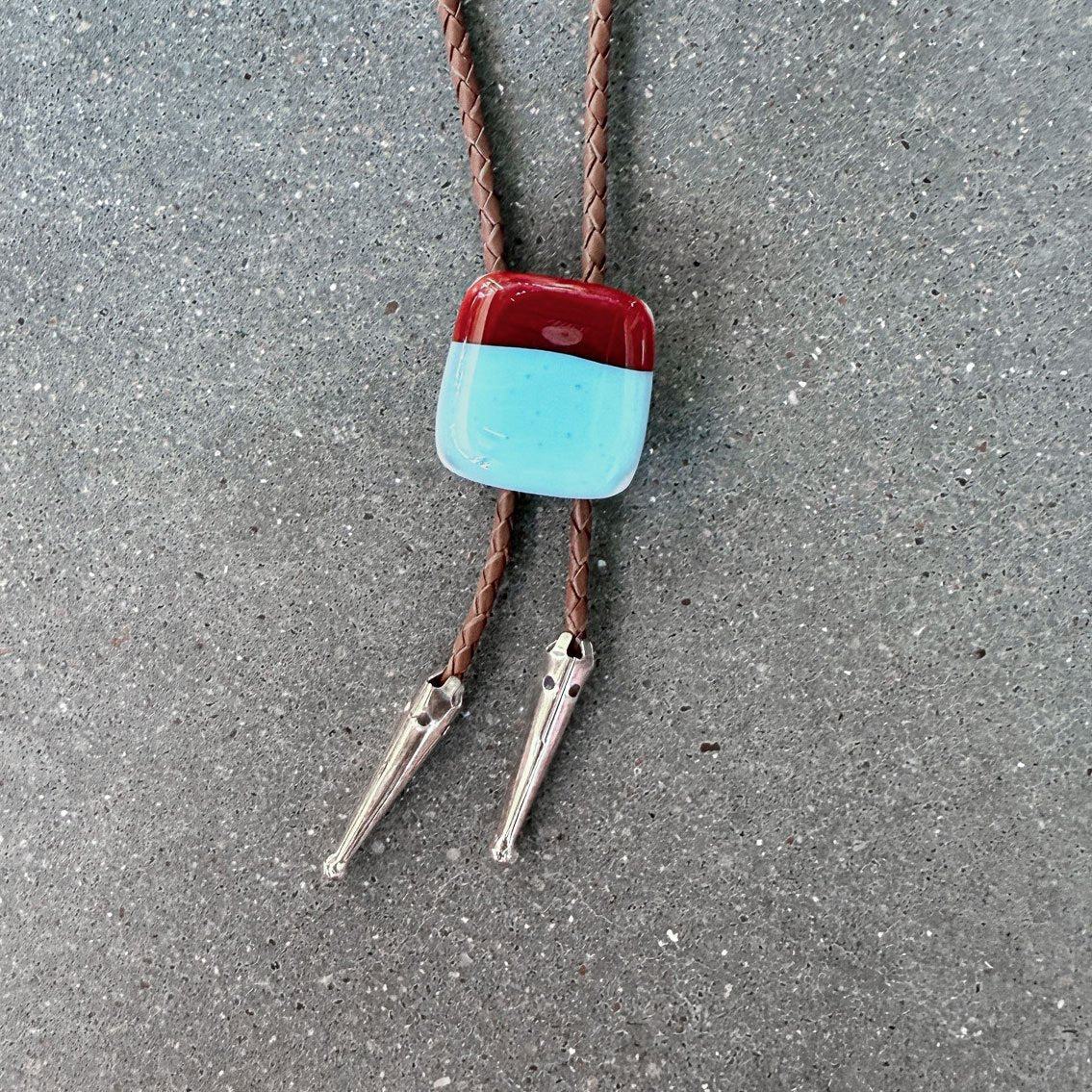 65b2bb63f348b87cbe1f70aa_clover-maven-22-glass-bolo-tie-red-blue-square-brown-cord-silver-tips_1784393137768.jpg