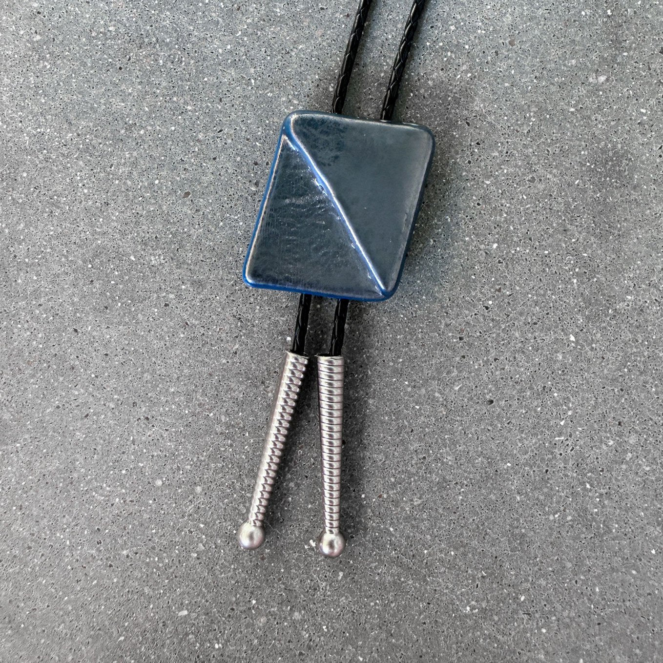 65b2bb63f348b87cbe1f70aa_clover-maven-23-glass-bolo-tie-gray-rectangle-black-cord-silver-tips_1784392206759.jpg