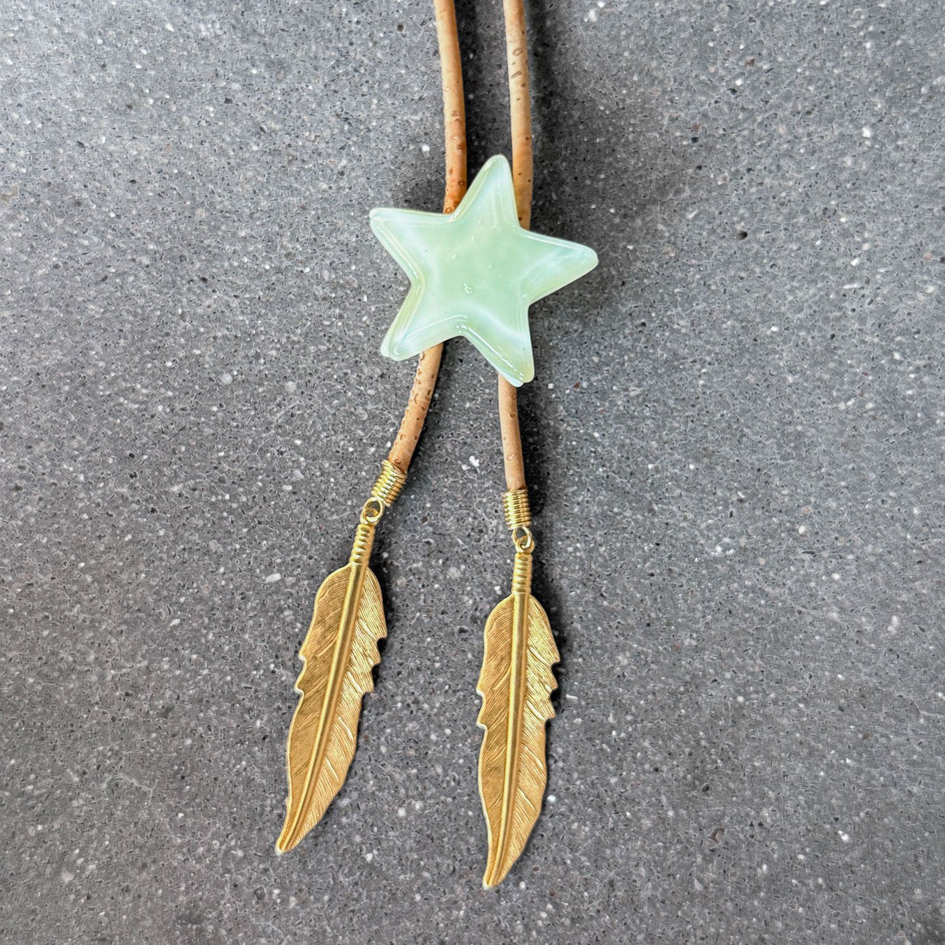 65b2bb63f348b87cbe1f70aa_clover-maven-9-glass-bolo-tie-green-star-tan-cord-gold-tips_1784383446924.jpg